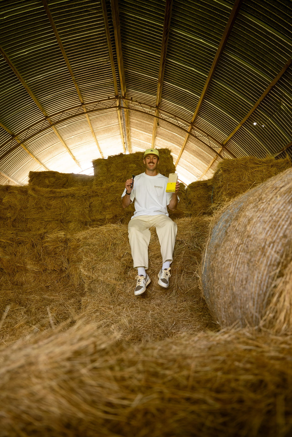 Flynny's founder sitting in a hay barn holding a razor and packaging